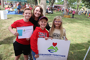 Image of children and woman holding Stronger Together: Akron Westfield Heart & Soul at community event