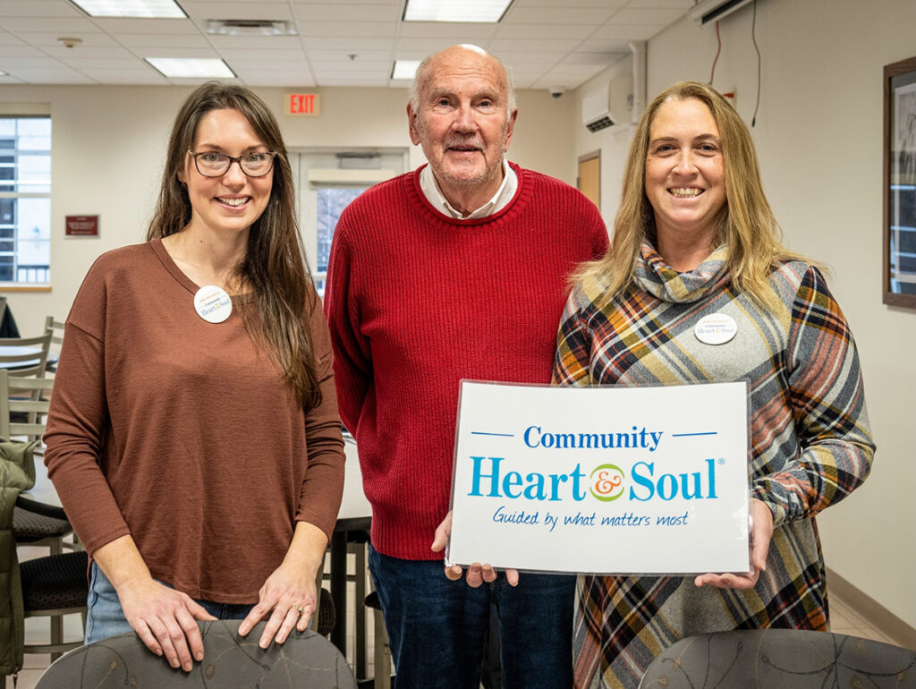 Image of Pittsfield Maine Community Heart & Soul team members holding sign with Community Heart & Soul logo