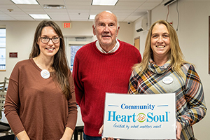 Image of Pittsfield Maine Community Heart & Soul team members holding sign with Community Heart & Soul logo
