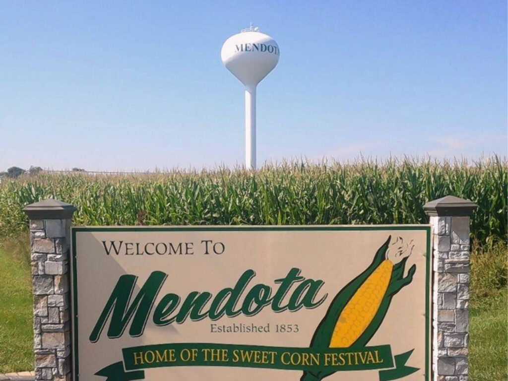 Mendota, Illinois town welcome sign with corn cob and water tower in background