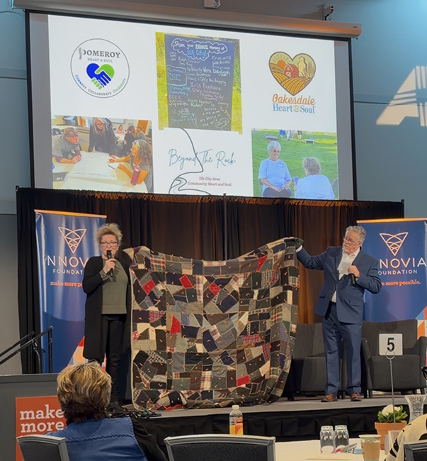 Picture from Innovia Summit with Community Heart & Soul VP of Market Development, Al Getler, holding up a quilt made of multiple pieces