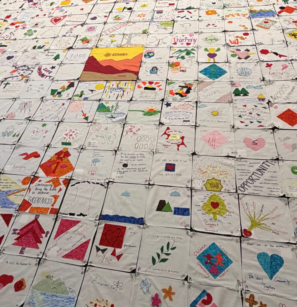 Picture of a beautiful quilt with multiple different squares created by different community members displayed at the Innovia Foundation Summit Event