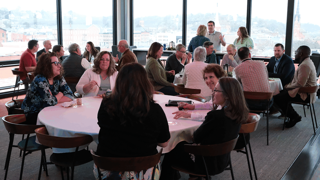 Picture of people sitting at tables and standing and chatting at the rooftop celebration at Dupaco Voices building in downtown Dubuque, Iowa.