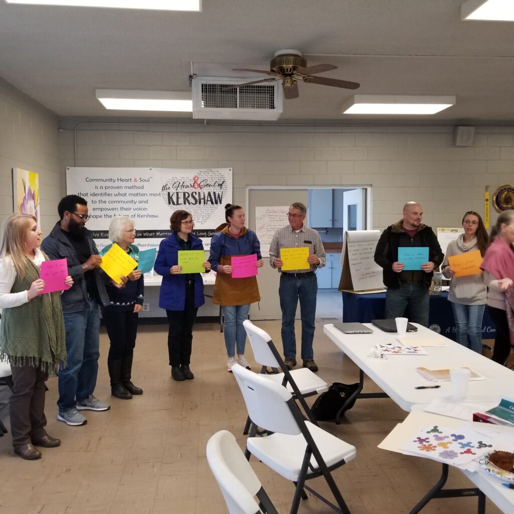 Picture of residents and volunteers holding signs during community engagement training by Kershaw Heart & Soul team
