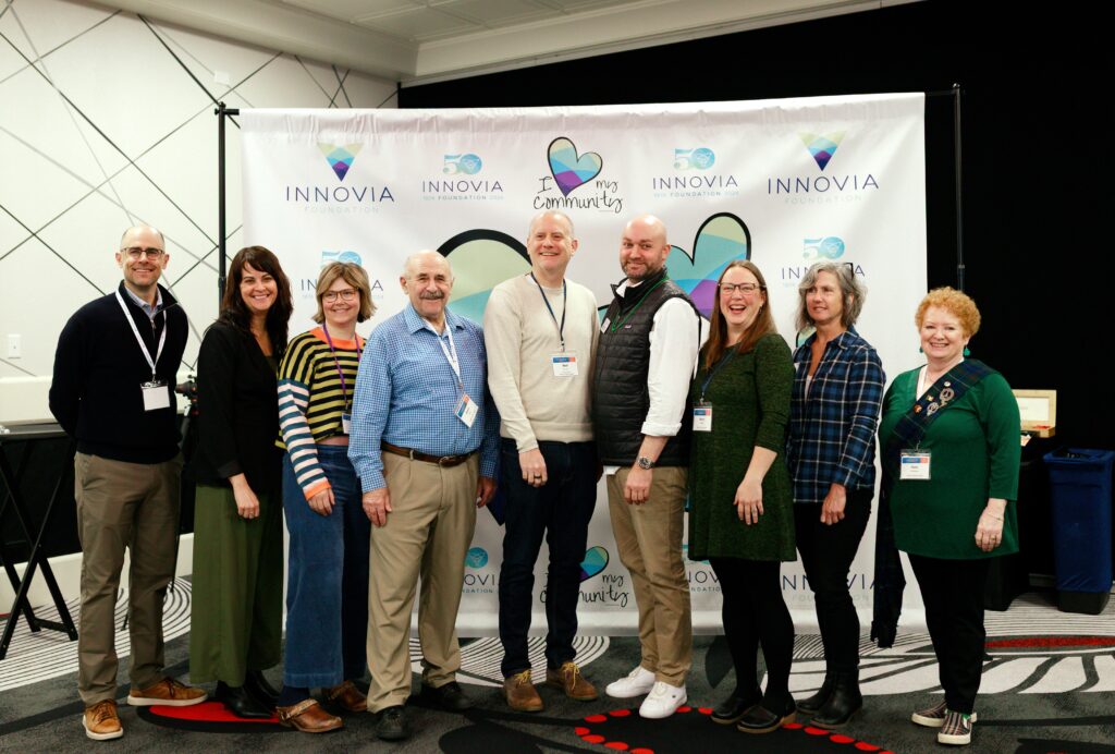 Picture of a group of volunteers, residents and staff for the Innovia Foundation in front of logo banner